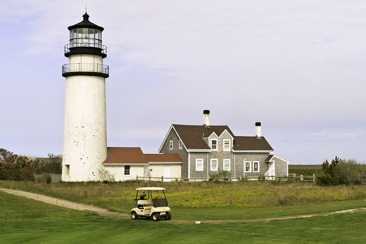 Golf cart on a putting green path near the historic Cape Cod lighthouse